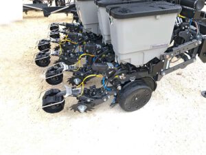 Nahaufnahme mehrerer Säelemente der Agrisem Chief mit Keeton Saatgut-Andrückern. Die Saatgutbehälter sind in Grau gehalten, während die einzelnen Säeinheiten schwarz sind und mit hydraulischen und pneumatischen Komponenten verbunden sind. Die Keeton Andrücker sorgen für eine gleichmäßige Ablage des Saatguts in der Furche.