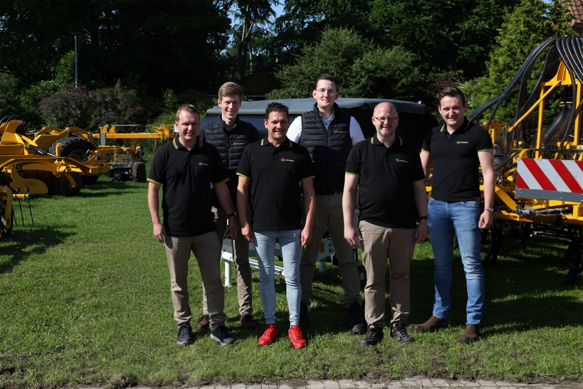 Teamfoto von AGRISEM Deutschland vor gelb-schwarzer Landtechnik im Außenbereich, mit mehreren Mitarbeitenden in Firmenkleidung.