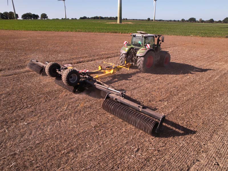 Agrisem Pack Roller mit breiten Walzensegmenten hinter einem Traktor bei der Bodenbearbeitung auf einem Acker.