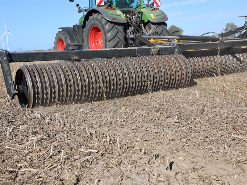 Nahaufnahme der profilierten Walzenringe eines Agrisem Pack Rollers bei der Bodenbearbeitung hinter einem Traktor. Titel: